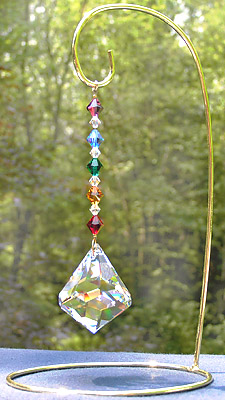 Bell 50mm Crystal With Rainbow Crystal Beads which Echo the Crystal Shape. Overall Length is 5.5 Inches. Shown with Medium Size Brass Ornament Stand, 8.5 Inches High.